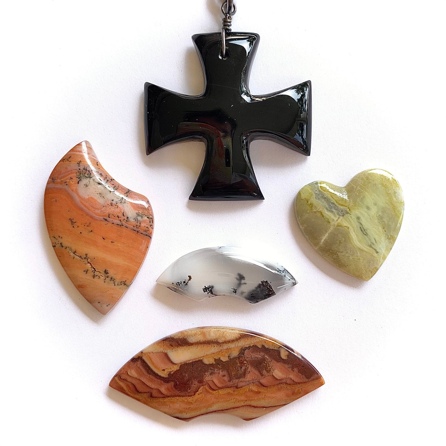 Black obsidian cross pendant with four different stone fancy cabochons on a white background